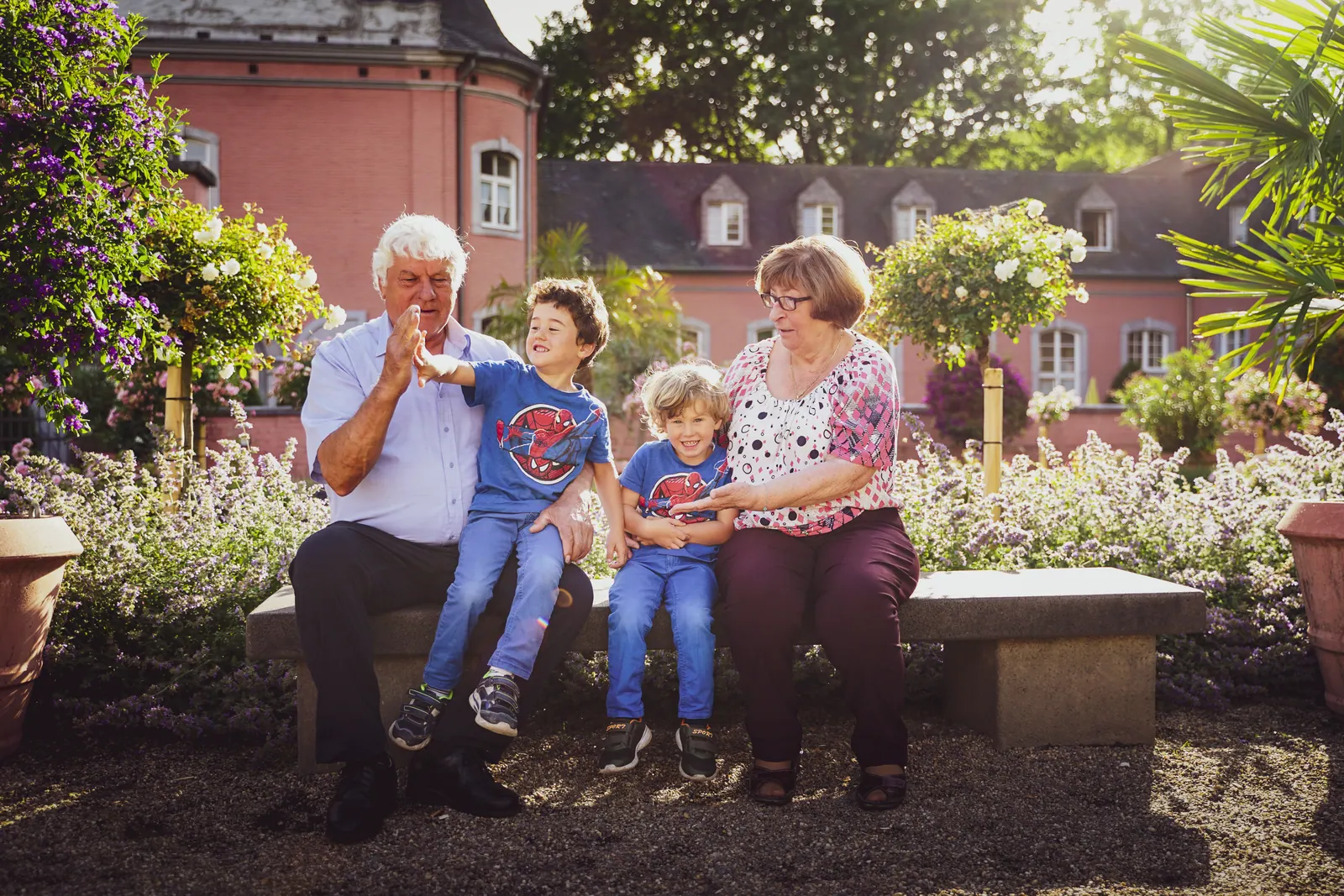 Großeltern pusten mit zwei Kindern Seifenblasen auf einer Gartenbank