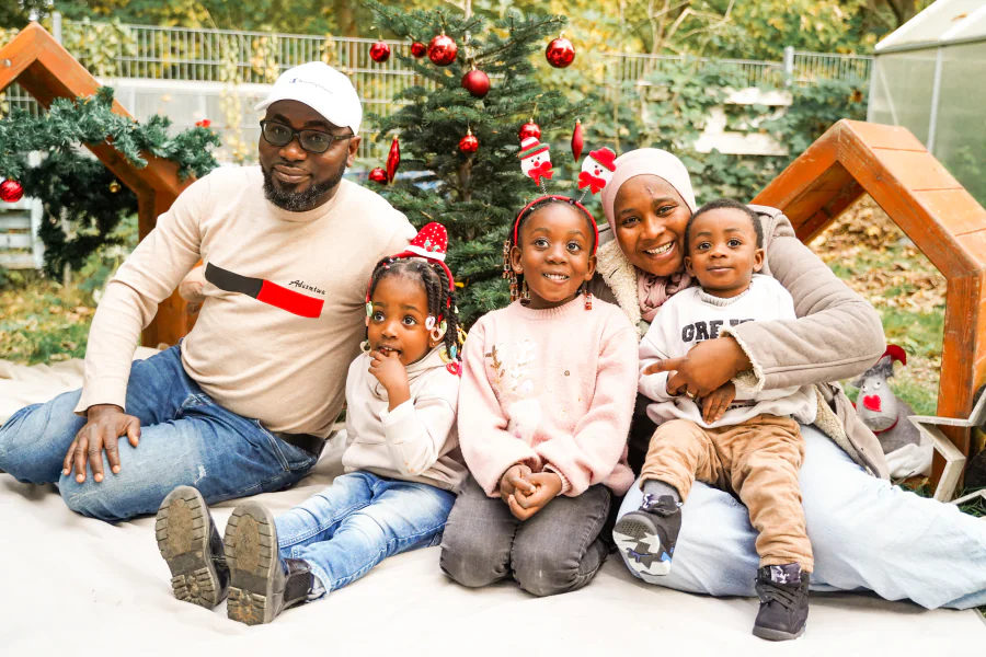 Eine sechsköpfige Familie sitzt vor einer weihnachtlich geschmückten Kulisse