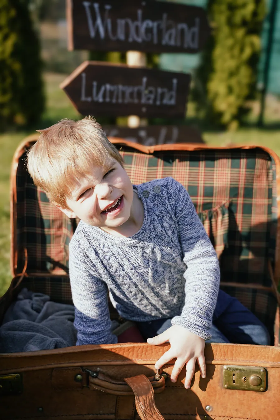 Ein lachender Junge sitzt in einem offenen Vintage-Koffer