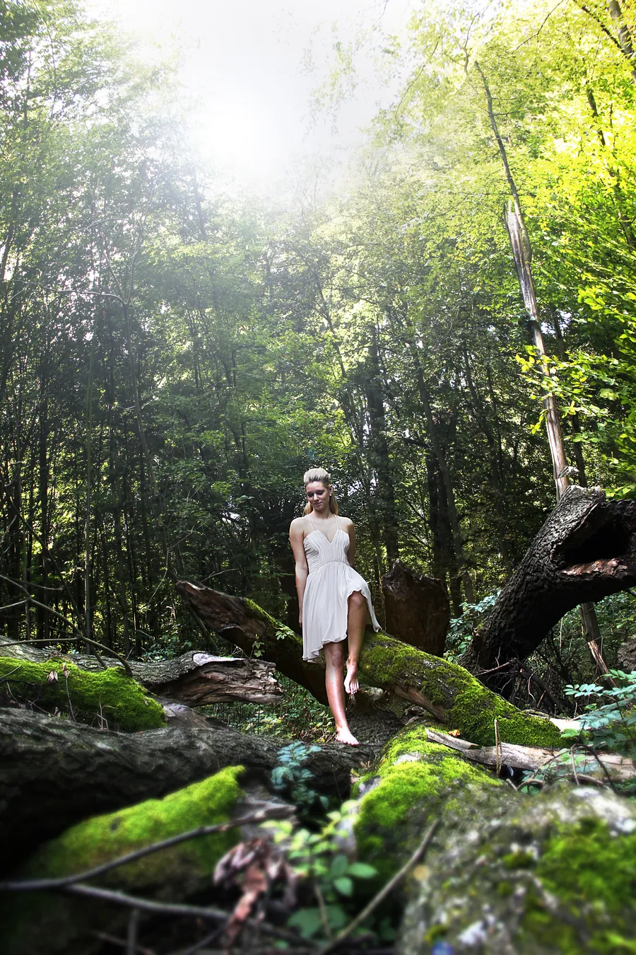 Eine Frau im weißen Kleid geht durch einen moosigen Wald mit Sonnenstrahlen