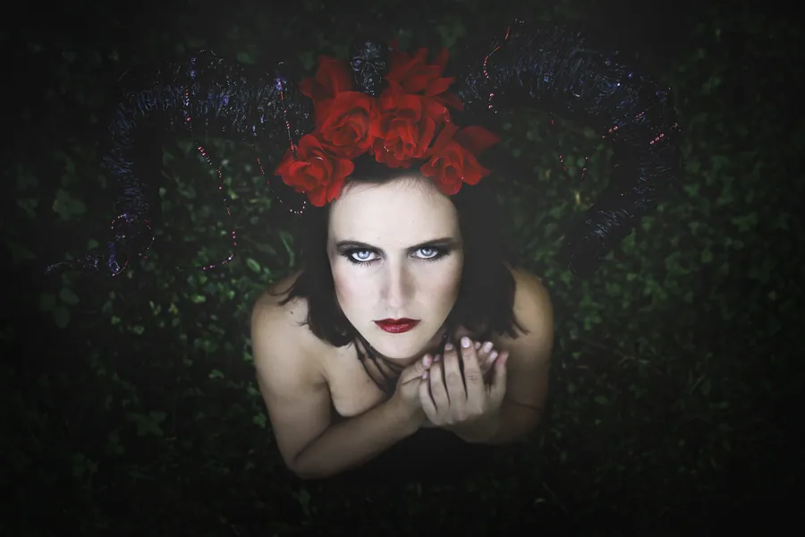 Dunkles Portrait einer Frau mit roten Rosen im Haar