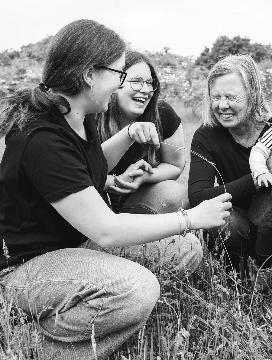 Schwarzweißbild: Drei Frauen sitzen lachend zusammen in einer Wiese
