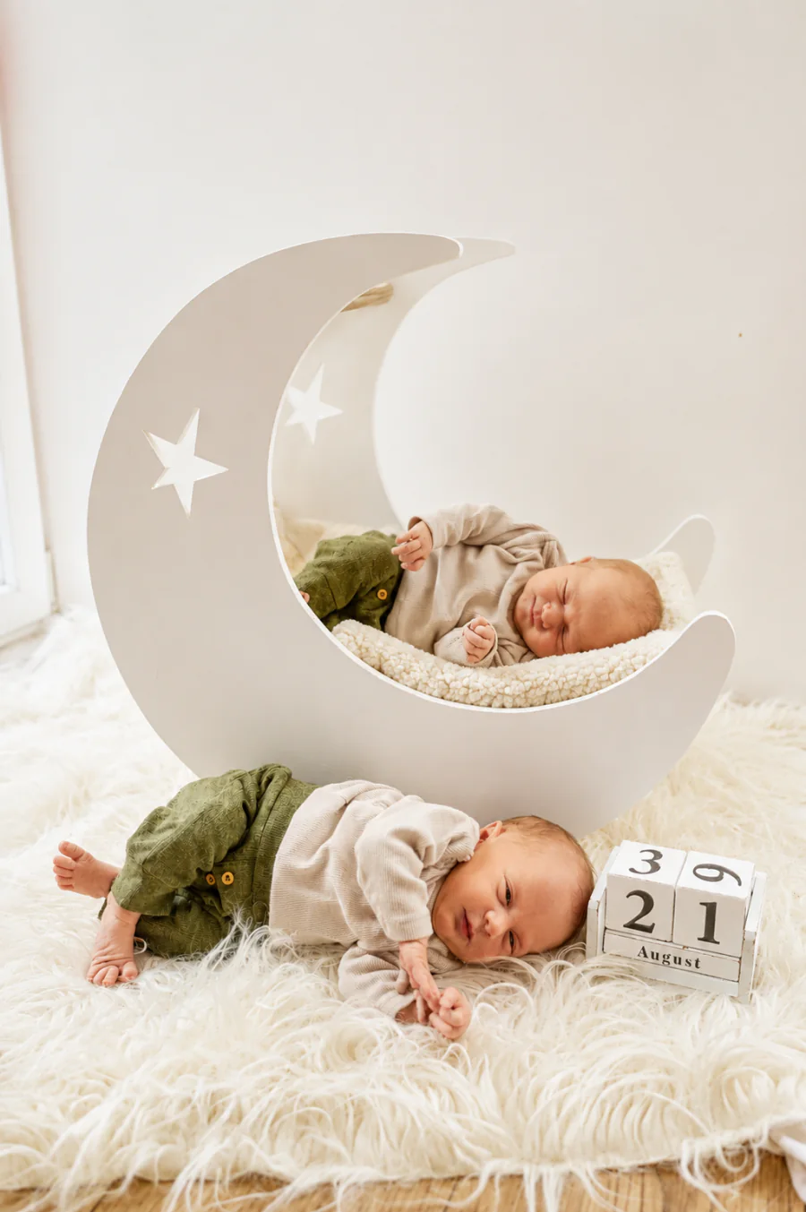 Zwei Neugeborene liegen vor und in einer weißen Mondkulisse auf einer hellen Decke