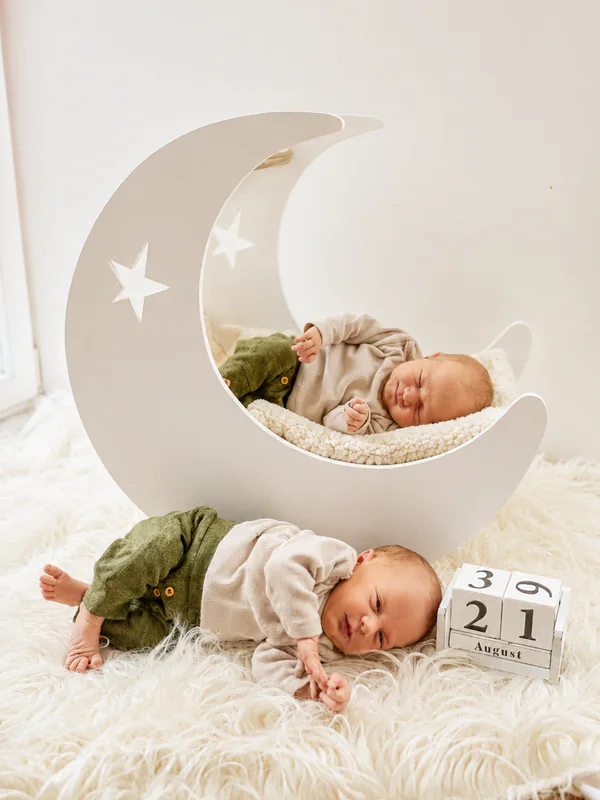 Zwei Neugeborene liegen vor und in einer weißen Mondkulisse auf einer hellen Decke
